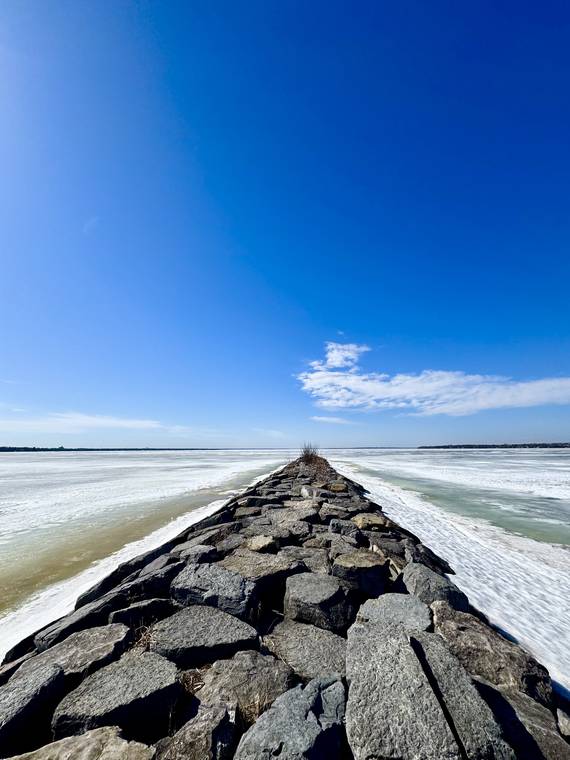 A stone breakwater leading into an icy lake in Ottawa, Canada