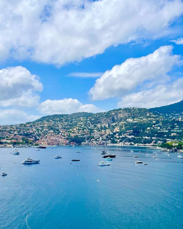 Boats on the blue bay below a hillside town in Nice, France